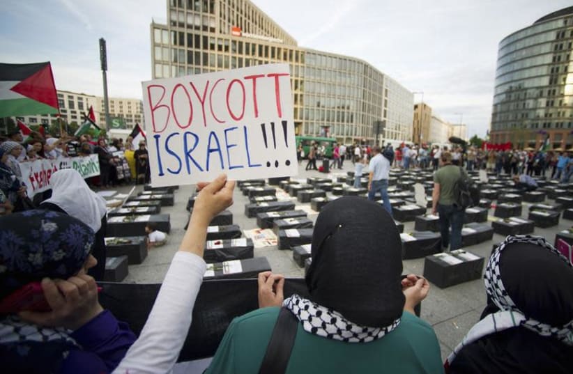 A woman holds a sign which reads "Boycott Israel" in front of symbolic coffins while attending a demonstration supporting Palestine, in Berlin August 1, 2014. Israel launched its Gaza offensive on July 8 in response to a surge of rocket attacks by Gaza's dominant Hamas Islamists. Hamas said that Pal (photo credit: REUTERS/STEFFI LOOS)