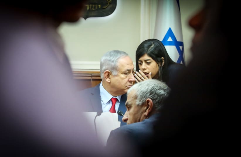 An aide whispers to Prime Minister Benjamin Netanyahu, with Moshe Kahlon in the foreground, at a cabinet meeting, December 9th, 2018 (photo credit: MARC ISRAEL SELLEM/THE JERUSALEM POST)