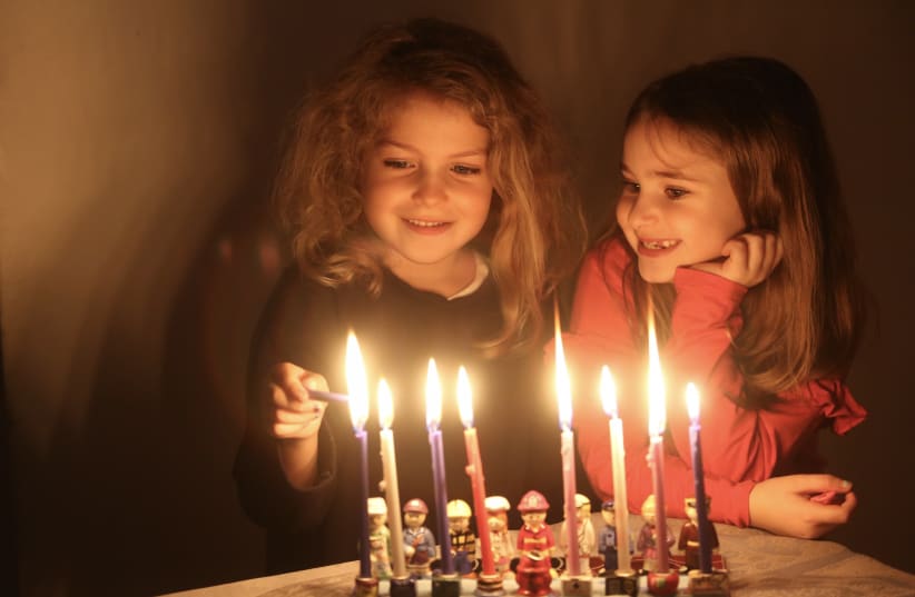 Leni (blonde hair) and Tali lighting the last candle of Hannukah, 2018. (photo credit: MARC ISRAEL SELLEM)