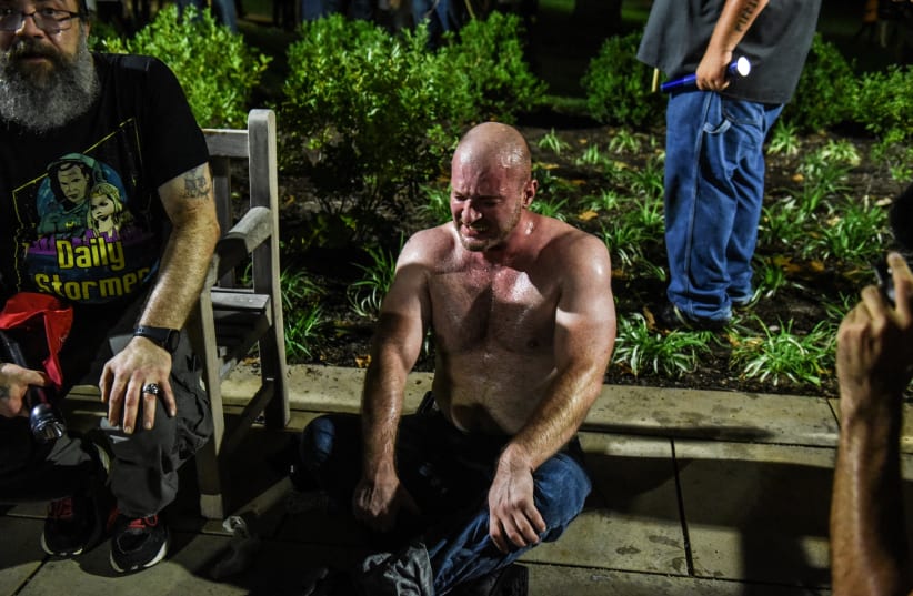 Christopher Cantwell recovers from being pepper-sprayed as he and other white nationalists participate in a torch-lit march on the grounds of the University of Virginia ahead of the Unite the Right Rally in Charlottesville, Virginia on August 11, 2017 (photo credit: STEPHANIE KEITH/REUTERS)