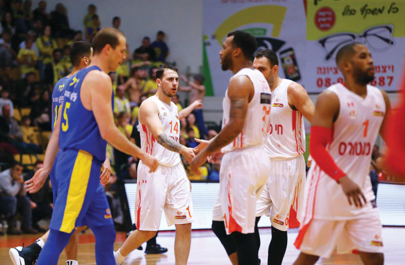 Ironi Ness Ziona players (in white) celebrate their 83-81 victory over Maccabi Tel Aviv in Basketball Super League action this week (photo credit: ERAN LUF)
