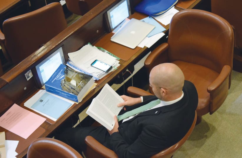 Likud MK Amir Ohana reads during a debate in the Knesset plenum  (photo credit: Courtesy)