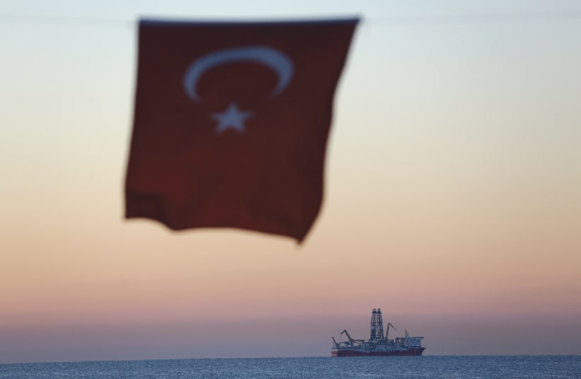 A TURKISH national flag hangs in the foreground as drilling vessel ‘Fatih’ is seen off the Mediterranean resort city of Antalya, Turkey, in October (photo credit: REUTERS)