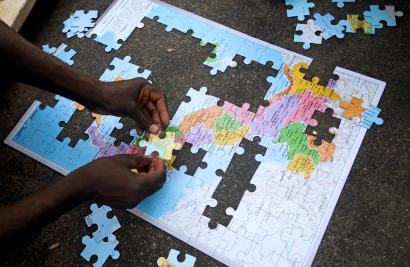 Migrants assemble a puzzle depicting Italy on a map, at a makeshift camp in Via Cupa (Gloomy Street) in downtown Rome, Italy, August 2, 2016 (photo credit: REUTERS/MAX ROSSI)