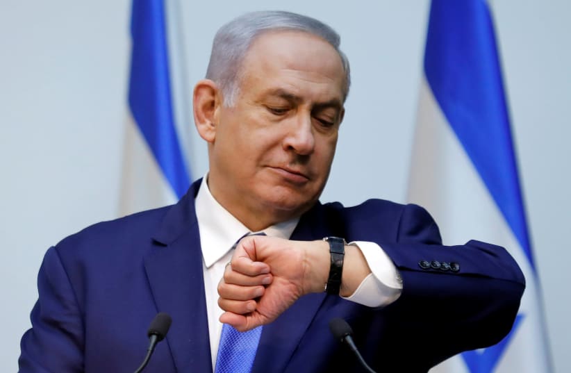 Israeli Prime Minister Benjamin Netanyahu looks at his watch before delivering a statement at the Knesset, Israel's parliament, in Jerusalem December 19, 2018 (photo credit: AMIR COHEN/REUTERS)