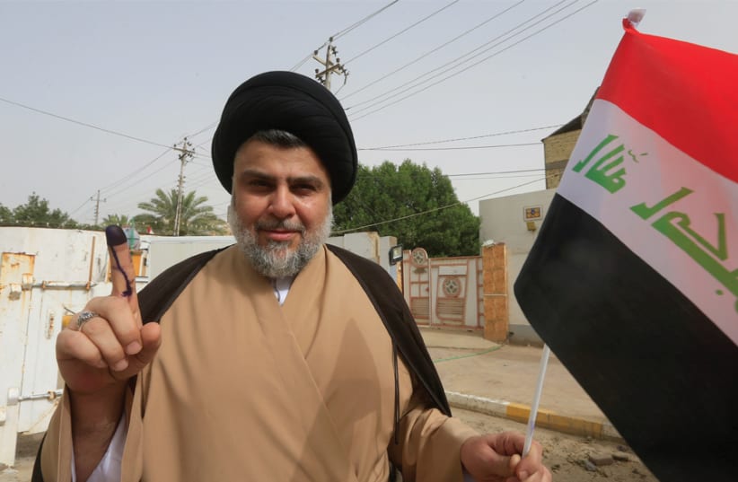 IRAQI SHI’ITE cleric Muqtada al-Sadr shows his ink-stained finger after casting his vote at a polling station during the parliamentary election in Najaf, Iraq, on May 12. (photo credit: REUTERS)