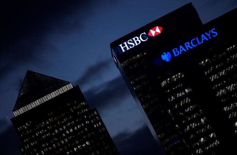 HSBC and Barclay's buildings are lit up at dusk in the Canary Wharf financial district of London, Britain, November 19, 2018 (photo credit: TOBY MELVILLE/REUTERS)