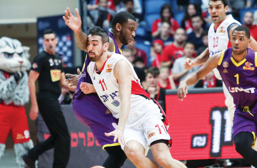 Hapoel Jerusalem’s Bar Timor drives to the basket against the Hapoel Holon defense during the Reds’ 94-74 home victory over Holon in Basketball Super League action this week (photo credit: DANNY MARON)