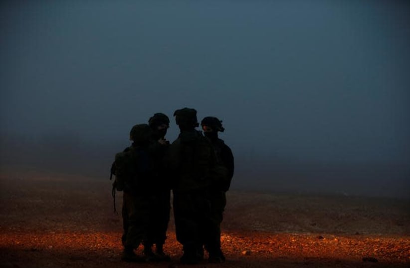 Israeli soldiers stand near the area where Israeli military personnel continue their work on exposing and thwarting cross-border tunnels dug from Lebanon into Israel, as seen on the Israeli side of the border, near the town of Metula December 19, 2018 (photo credit: RONEN ZVULUN / REUTERS)