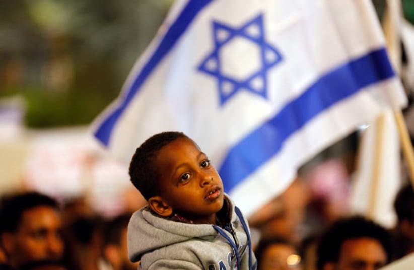 A boy takes part in a protest against the Israeli government's plan to deport African migrants, in Tel Aviv, Israel March 24, 2018.  (photo credit: REUTERS/CORINNA KERN)