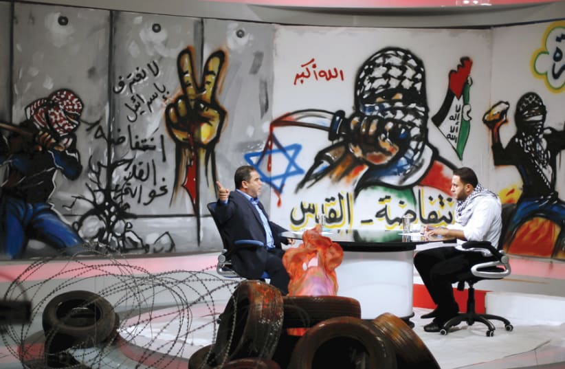 PALESTINIAN PRESENTER Raji Al-Hams (right) listens to Hamas official Salah al-Bardweel at the studio of Hamas-run al-Aqsa TV in Gaza City in 2015. The studio is decorated with slogans praising the ‘Knife Intifada.’ (photo credit: REUTERS)