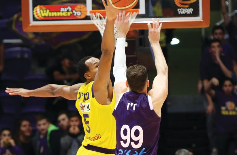 HAPOEL HOLON forward Darion Atkins (left) blocks a shot by Ironi Nahariya’s Yiftach Ziv during first-place Holon’s 78-72 victory on Wednesday night in BSL action (photo credit: UDI ZITIAT)