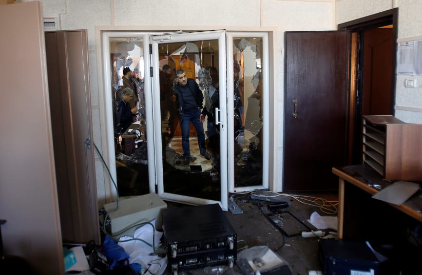 Palestinians inspect the damage inside the office of Palestine TV, in Gaza City January 4, 2019 (photo credit: AHMED ZAKOT / REUTERS)