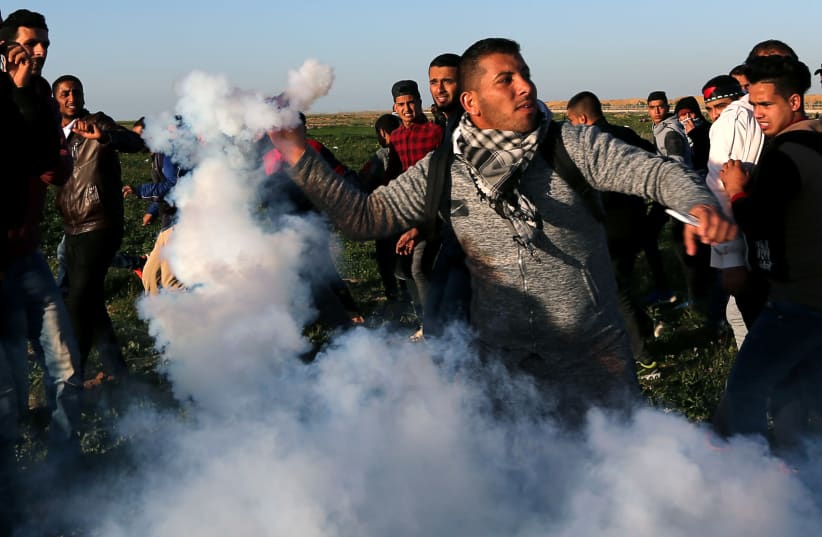A Palestinian demonstrator returns a tear gas canister fired by Israeli troops during a protest at the Israel-Gaza border fence, in the southern Gaza Strip January 4,2019 (photo credit: IBRAHEEM ABU MUSTAFA / REUTERS)