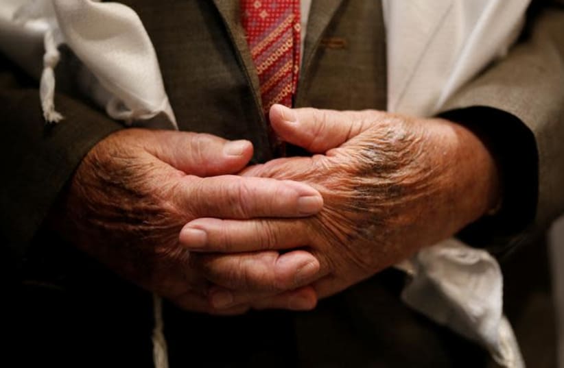 The hands of Shalom Shtamberg, a 93-year old Holocaust survivor, are seen during his bar mitzvah ceremony, a Jewish coming-of-age celebration traditionally marked by boys at the age of 13, in Haifa, Israel August 31, 2017 (photo credit: AMIR COHEN/REUTERS)