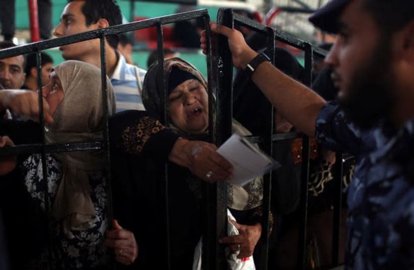 A woman gestures as she waits to travel into Egypt through Rafah border crossing after it was opened by Egyptian authorities for humanitarian cases, in the southern Gaza Strip. (photo credit: REUTERS/IBRAHEEM ABU MUSTAFA)