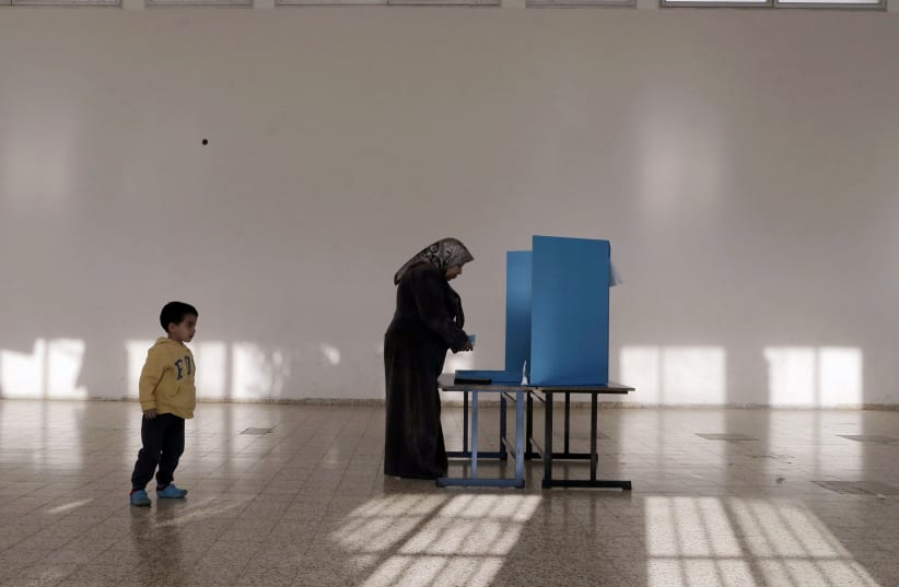 An Israeli Arab stands behind a voting booth before casting her ballot at a polling station in the northern town of Umm el-Fahm March 17, 2015. Millions of Israelis turned out to vote on Tuesday in a tightly-fought election, with Prime Minister Benjamin Netanyahu facing an uphill battle to defeat a  (photo credit: AMMAR AWAD / REUTERS)