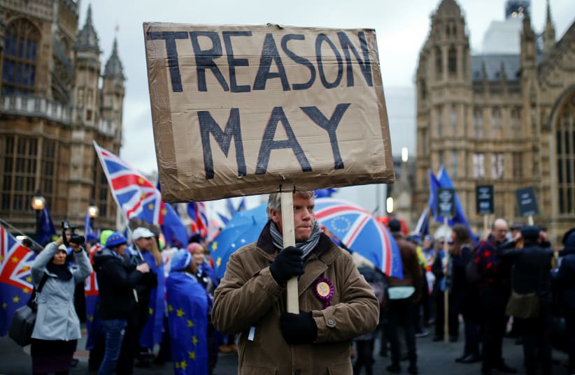 A pro-Brexit protester holds a banner as anti-Brexit protesters demonstrate outside the Houses of Parliament, ahead of a vote on Prime Minister Theresa May's Brexit deal, in London, Britain, January 15, 2019. (photo credit: REUTERS/HENRY NICHOLLS)