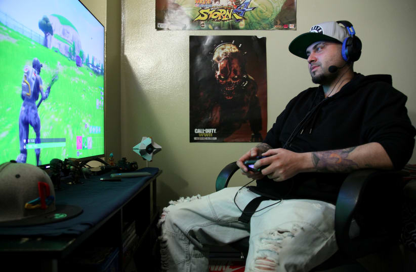Twenty Seven-year-old Christian Acevedo plays the video game 'Fortnite Battle Royale' from his home in Brooklyn, New York, U.S., on April 21, 2018. Acevedo says if he doesn't have to work the next day, he often stays up all night to play the popular game (photo credit: JILLIAN KITCHENER/REUTERS)