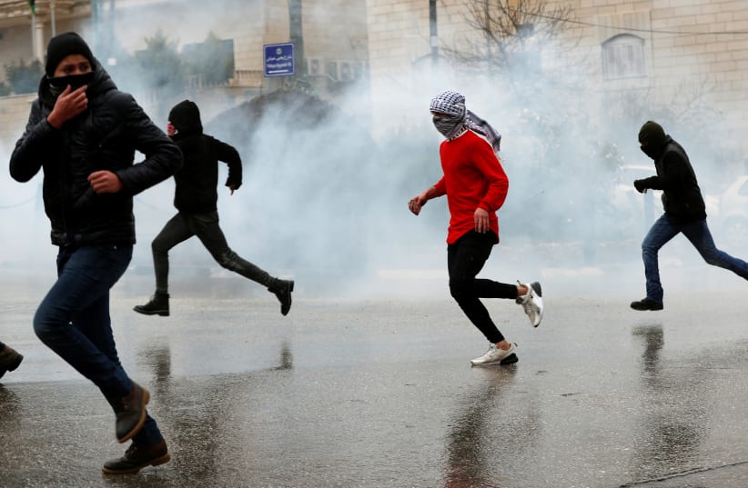 Palestinians run from Israeli forces in Ramallah, January 9, 2019 (photo credit: MOHAMAD TOROKMAN/REUTERS)