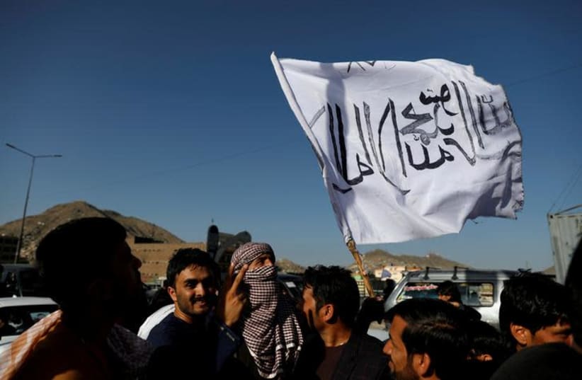A member of the Taliban holds a flag in Kabul, Afghanistan June 16, 2018. The writing on the flag reads: 'There is no god but Allah, Muhammad is the messenger of Allah' (photo credit: REUTERS/MOHAMMAD ISMAIL)