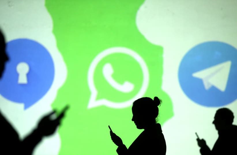 Silhouettes of mobile users next to the Whatsapp logo, March 28, 2018. (photo credit: REUTERS/ DADO RUVIC)