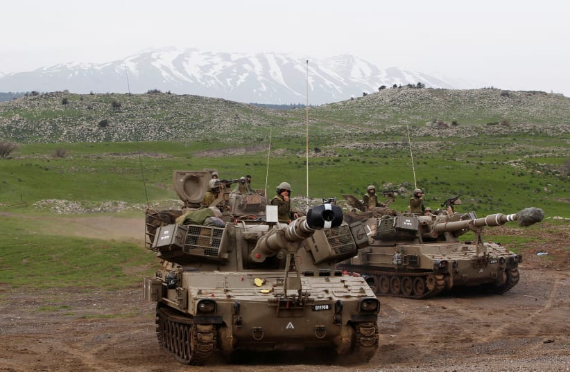 Mount Hermon is seen in the background as Israeli soldiers travel on mobile artillery units after an exercise in the Golan Heights, February 2013 (photo credit: BAZ RATNER/REUTERS)