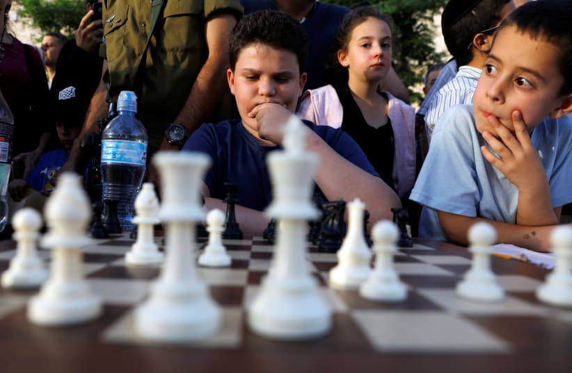Israelis wait for their turn to play against former Indian chess world champion Viswanathan Anand and former Russian chess world champion Anatoly Karpov (both not pictured) as they play simultaneous matches against tens of Israeli players during an event marking Israel's 70th anniversary at Jerusale (photo credit: REUTERS/Ronen Zvulun)