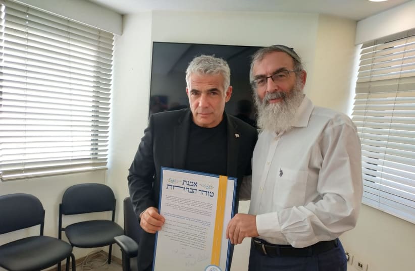 Yes Atid Party Leader Yair Lapid signs a vow of integrity and honesty ahead of the coming campaign with Rabbi David Stav, 2019. (photo credit: Courtesy)