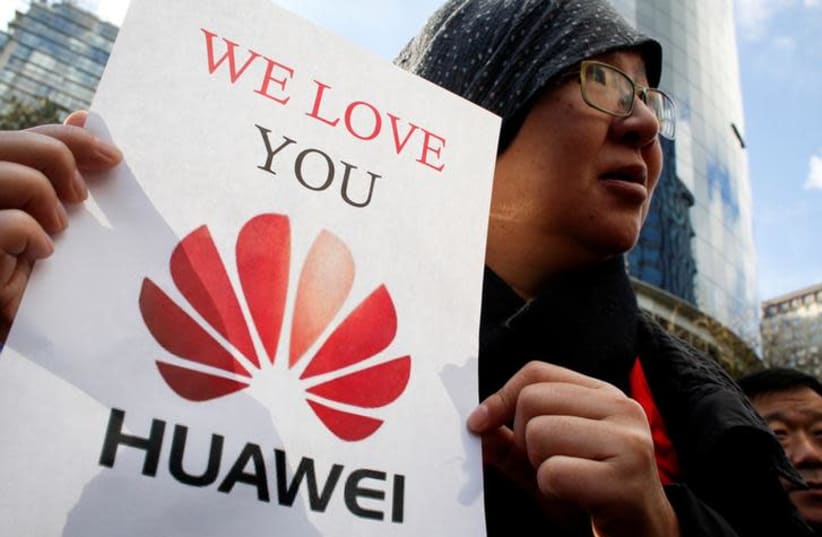Lisa Duan, a visitor from China, holds a sign in support of Huawei outside of the B.C. Supreme Court bail hearing of Huawei CFO Meng Wanzhou, who is being held on an extradition warrant in Vancouver, British Columbia, Canada (photo credit: REUTERS/DAVID RYDER)