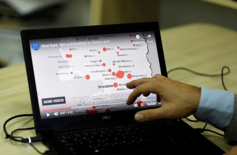 Omar Shakir, Israel and Palestine Director at Human Rights Watch, shows a map during an interview on home-renting company Airbnb's decision to remove listings in Israeli settlements, in Ramallah (photo credit: REUTERS/MOHAMAD TOROKMAN)