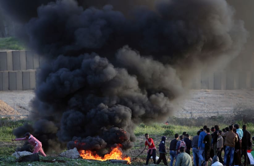 Palestinian demonstrators protest at the Israel-Gaza border fence, in the central Gaza Strip January 25, 2019 (photo credit: IBRAHEEM ABU MUSTAFA / REUTERS)