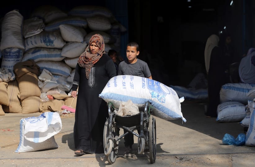 A Palestinian boy uses a wheelchair to transport a bag of peanuts as he helps his mother who makes a living by peeling peanuts for a factory, in Rafah in the southern Gaza Strip January 22, 2019. (photo credit: IBRAHEEM ABU MUSTAFA / REUTERS)