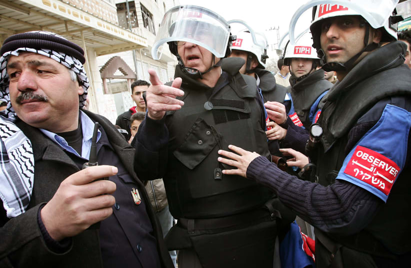 Arnstein Overkil, the Norwegian head of the TIPH observer team (C) coordinates with his staff and a Palestinian police officers outside TIPH headquarters in the West Bank city of Hebron February 8, 2006 (photo credit: DAMIR SAGOLJ/ REUTERS)