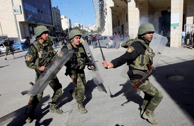 Members of Palestinian security forces disperse a Hamas demonstration in Hebron in the West Bank. December 14, 2018.  (photo credit: MUSSA QAWASMA / REUTERS)