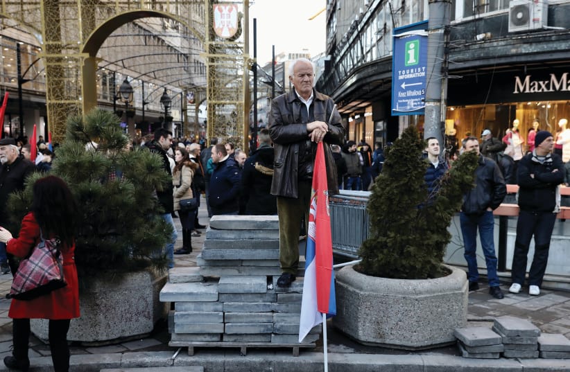 A MAN holds a Serbian flag on a street corner in Belgrade (photo credit: REUTERS)