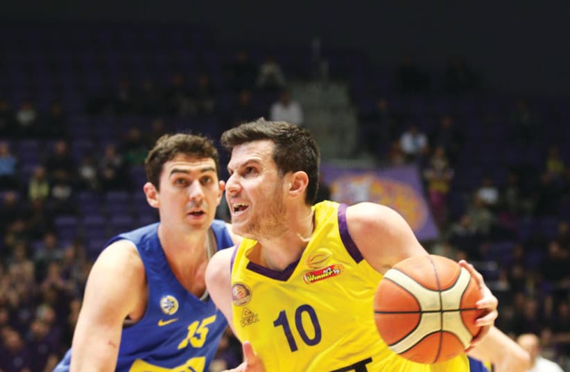 HAPOEL HOLON’S Guy Pnini (10) drives to the hoops past Maccabi Tel Aviv’s Jake Cohen during Holon’s 100-95 victory over the yellow-and-blue on Sunday night in BSL action (photo credit: ADI AVISHAI)