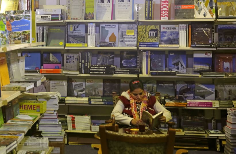 A woman reads a book inside the 49th Cairo International Book Fair in Cairo, Egypt February 1, 2018 (photo credit: AMR ABDALLAH DALSH / REUTERS)