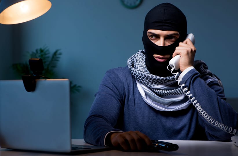 Terrorist burglar with gun working at computer (photo credit: INGIMAGE)