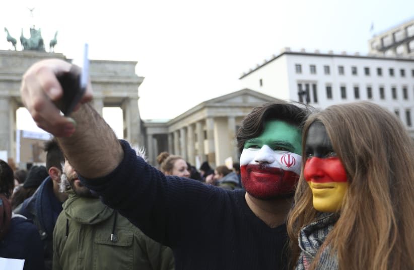 A couple, with their faces painted in the colours of Iranian and German national flags, takes a selfie during a rally against U.S. President Donald Trump's immigration policies outside the U.S. embassy in Berlin, Germany February 4, 2017 (photo credit: REUTERS/PAWEL KOPCZYNSKI)