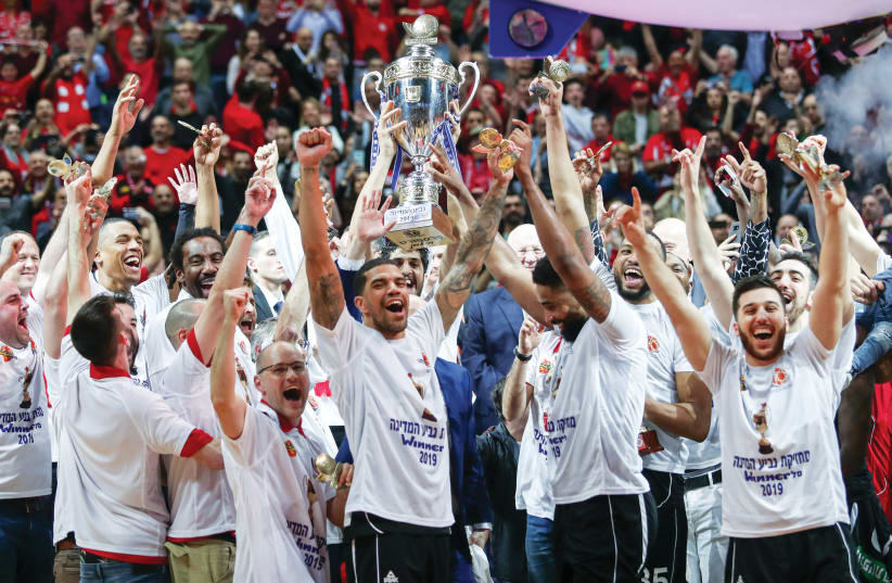 HAPOEL JERUSALEM celebrates on the court with the trophy following its victory over Maccabi Rishon Lezion in last week’s State Cup final in the capital (photo credit: DANNY MARON)