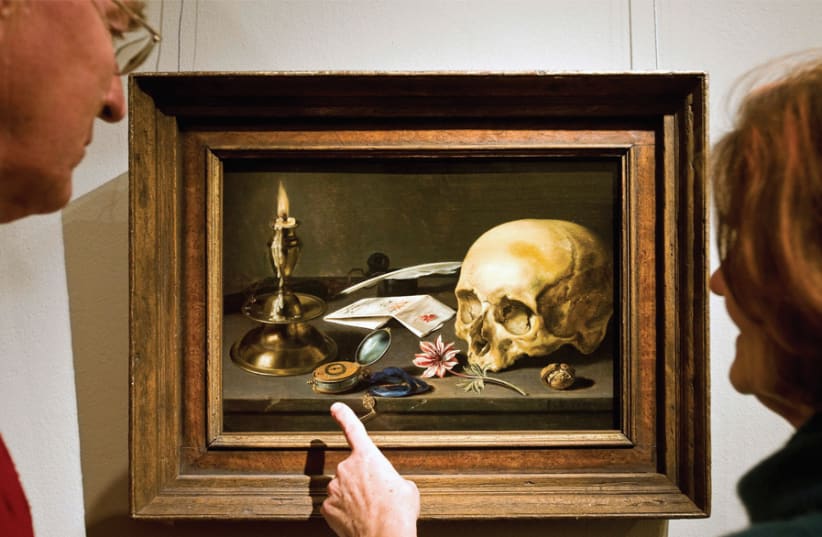 Visitors look at painter Pieter Claesz’s ‘Vanitas’ still life in the Frans Hals Museum in Haarlem, the Netherlands; snuffed-out candles, skulls and hourglasses were how the Old Masters portrayed the vanity of greed (photo credit: ROBIN VAN LONKHUIJSEN / UNITED PHOTOS / REUTERS)