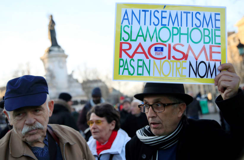 People attend a national gathering to protest antisemitism and the rise of antisemitic attacks in the Place de la Republique in Paris, France, February 19, 2019. The writing on the sign reads: "Antisemitism, islamophobia, racism - not in our name" (photo credit: REUTERS/GONZALO FUENTES)