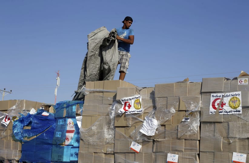 A Palestinian man checks a truck loaded with medical aid after entering Gaza at the Kerem Shalom crossing, in Rafah in the southern Gaza Strip August 28, 2014. An open-ended ceasefire in the Gaza war held on Wednesday as Prime Minister Benjamin Netanyahu faced strong criticism in Israel over a costl (photo credit: IBRAHEEM ABU MUSTAFA/REUTERS)