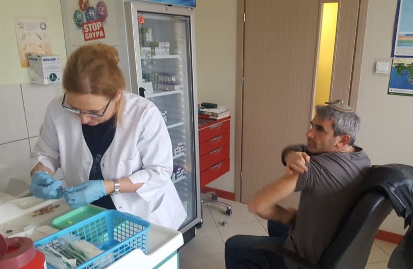 A parent of one of the students [R] getting vaccinated in Warsaw (photo credit: Courtesy)