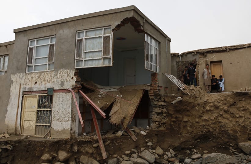 Afghans stand near a destroyed house after floods in the Shakar Dara district of Kabul August 11, 2013.At least 22 people in Afghanistan were killed and farmland was damaged when flash floods hit a plain near the capital, officials said on Sunday (photo credit: REUTERS)