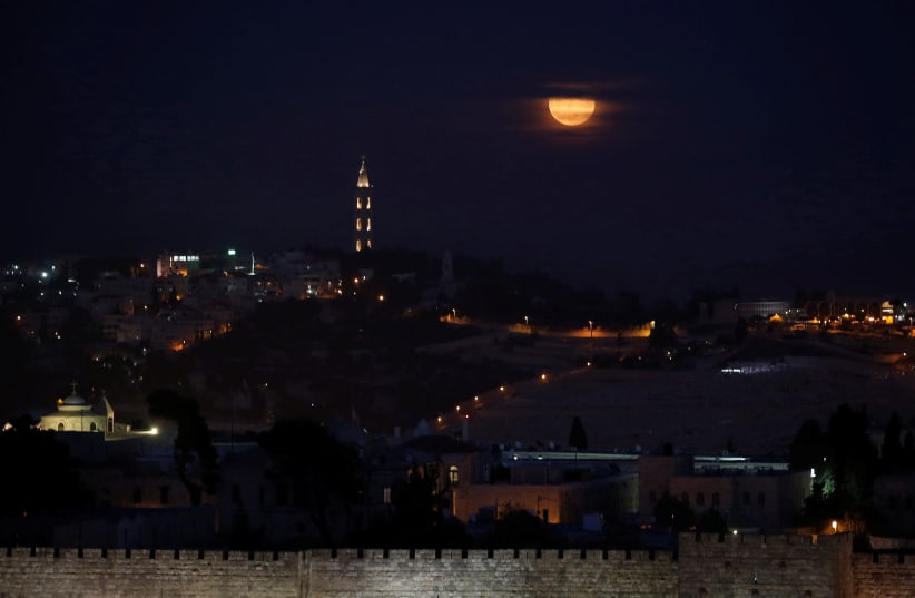 A "super moon" rises behind the Mount of Olives cemetery in Jerusalem looking towards Maale Adumim, November 14, 2016 (photo credit: RONEN ZVULUN / REUTERS)