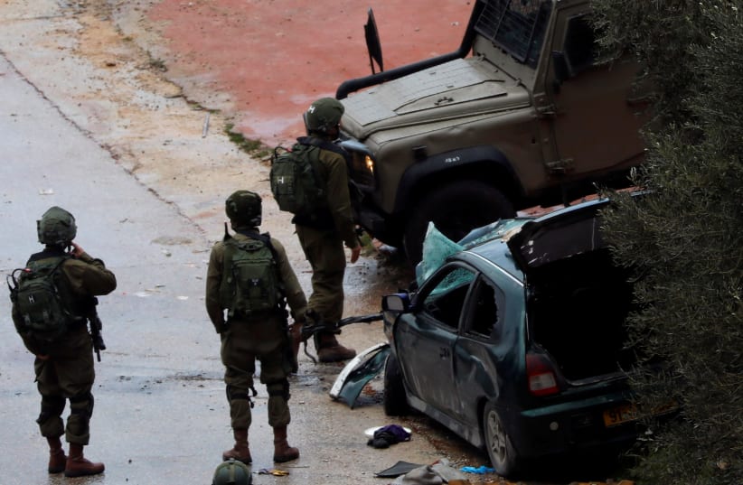 Israeli forces stand at the scene of a car ramming in the West Bank that injured two soldiers, March 4, 2019 (photo credit: REUTERS/MOHAMAD TOROKMAN)