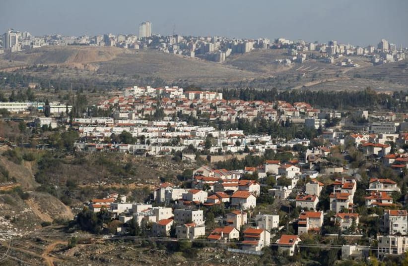 Houses are seen in the Israeli community of Givat Zeev (bottom) with the Palestinian Authority city of Ramallah in the background, December 29, 2016 (photo credit: BAZ RATNER/REUTERS)