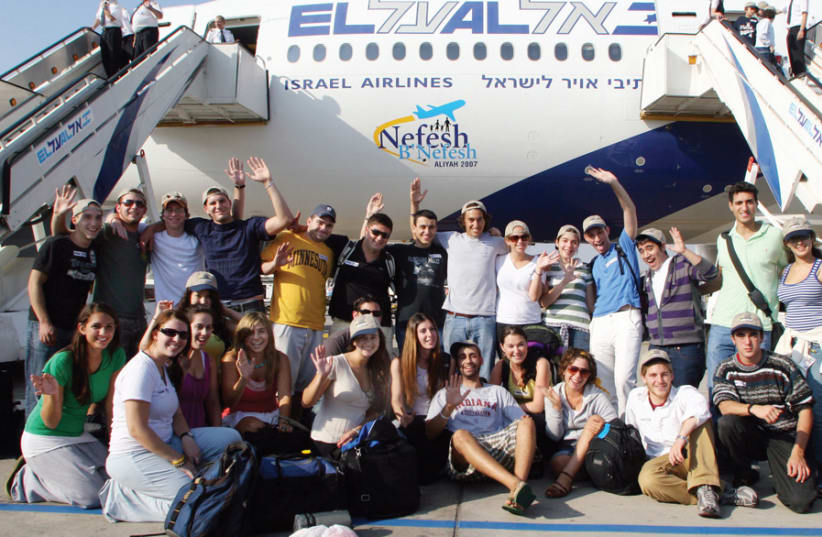 NEW ‘OLIM’ wave excitedly after arriving in Israel on a Nefesh B’Nefesh charter flight. (photo credit: Wikimedia Commons)